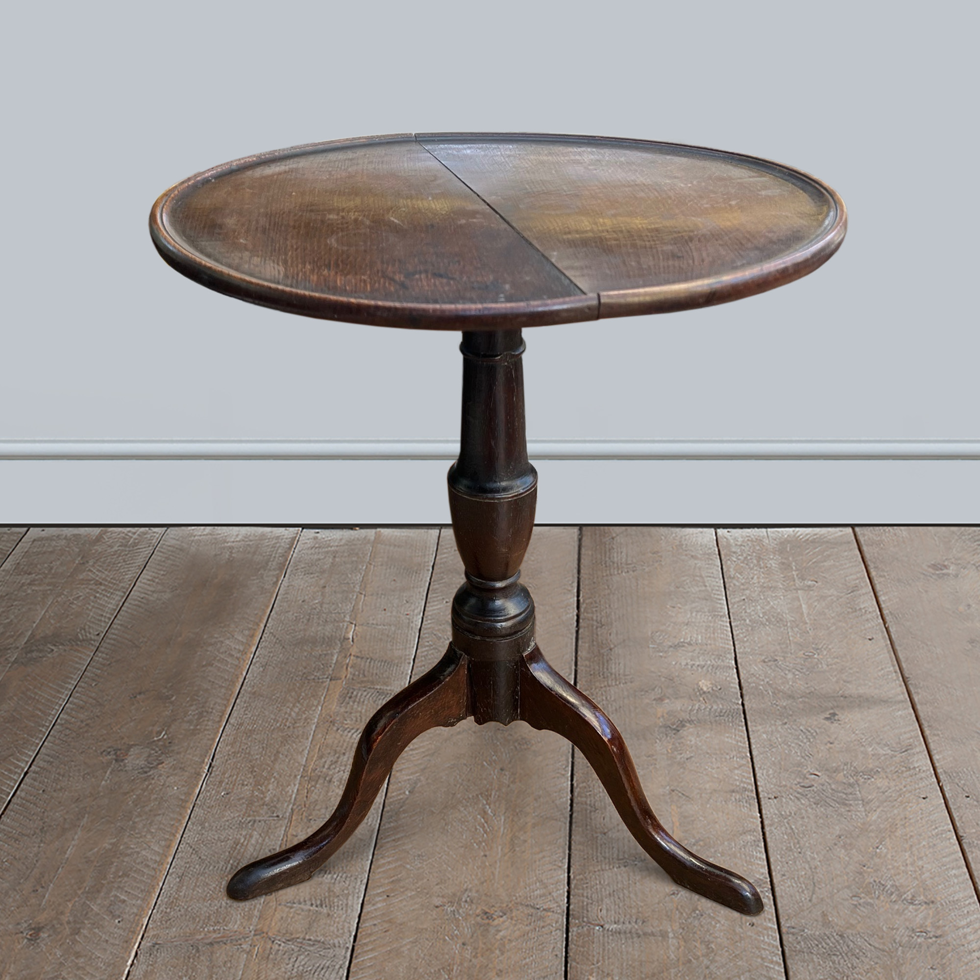 An early 19th century oak tripod table with baluster column and circular tray top.